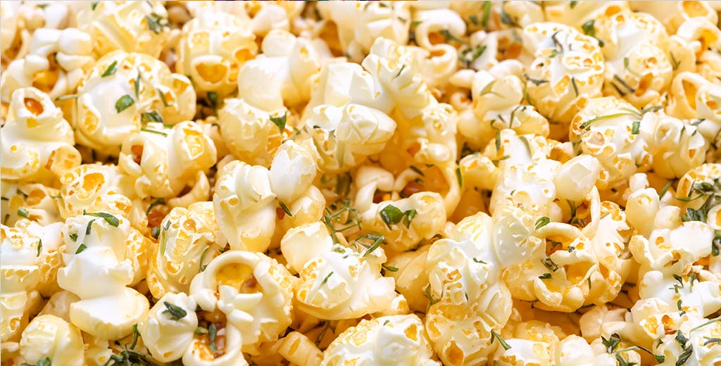 A close-up of popcorn kernels topped with green herbs