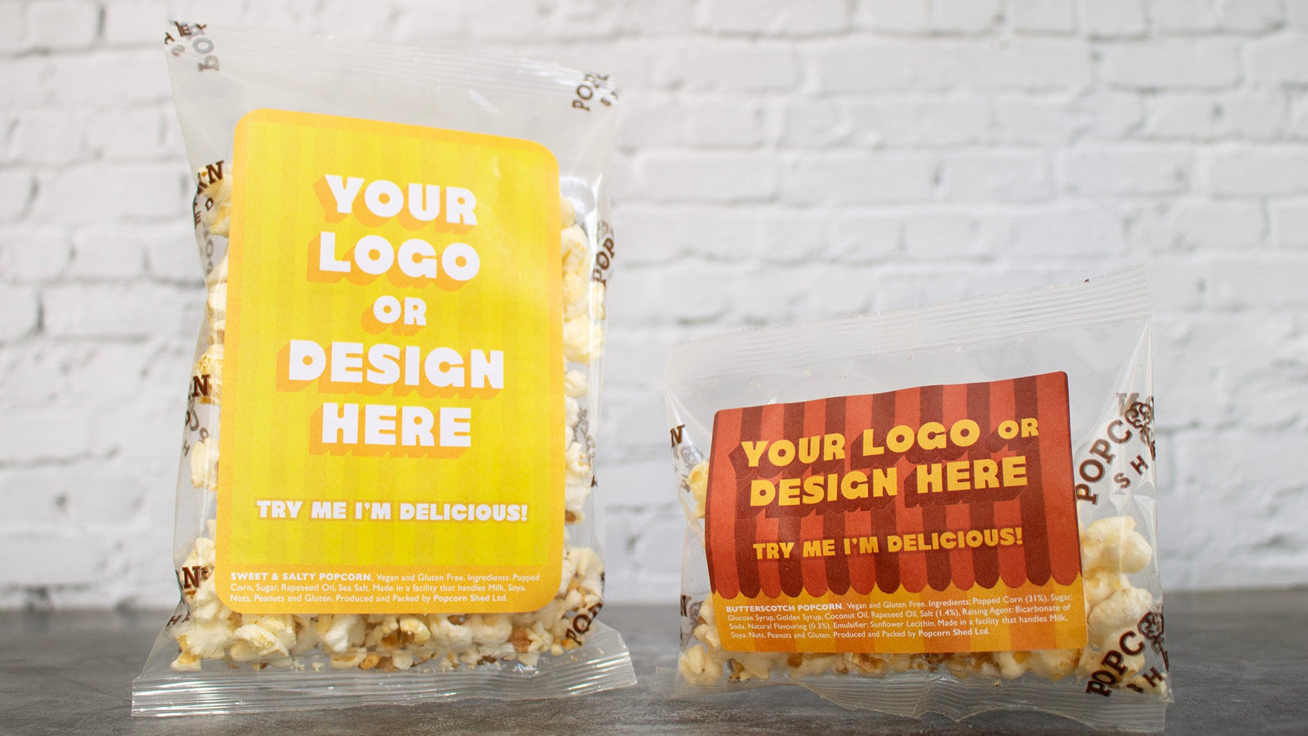 Two popcorn bags with customizable labels against a white brick wall background