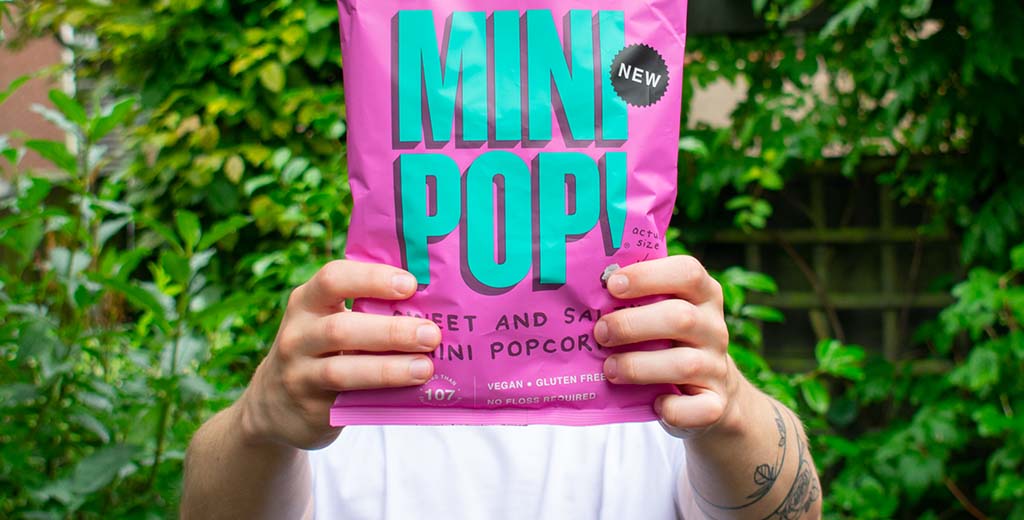 Two hands holding a bag of Popcorn Shed's Sweet & Salty popcorn, a popular snack choice for gut health 